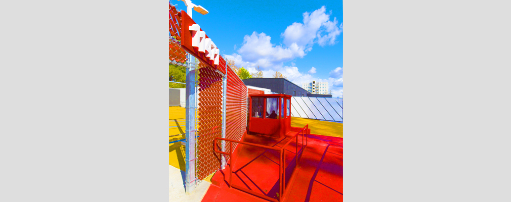 Photograph of a red-painted security kiosk with a guard inside.