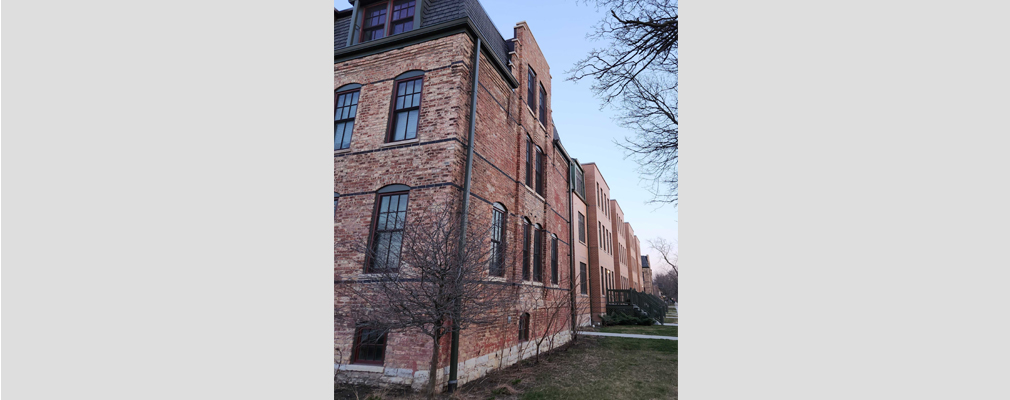 Ground-level view of the corner of a three-story brick historic building.