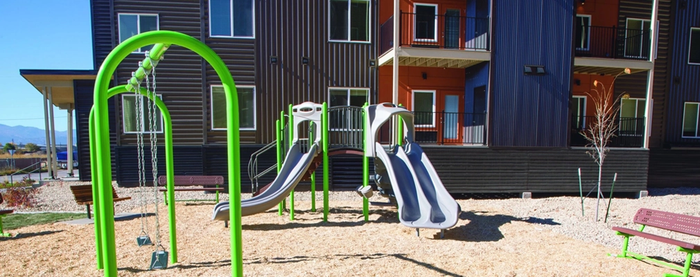 A colorful playground next to an apartment building.