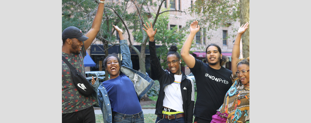Photograph of five young adults celebrating with raised hands.