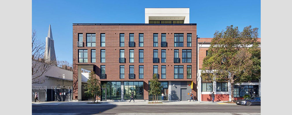 Head-on view of a four-story building situated between one- and two- story buildings.