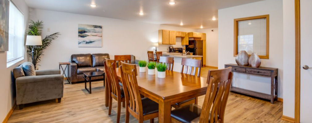 A modern living room with hardwood flooring, a sofa, a dining table, and chairs.