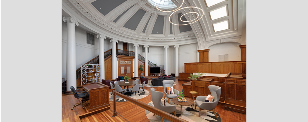 Photograph of the clubroom at Courthouse Lofts, with chairs and tables arranged within the domed room of a former courtroom.