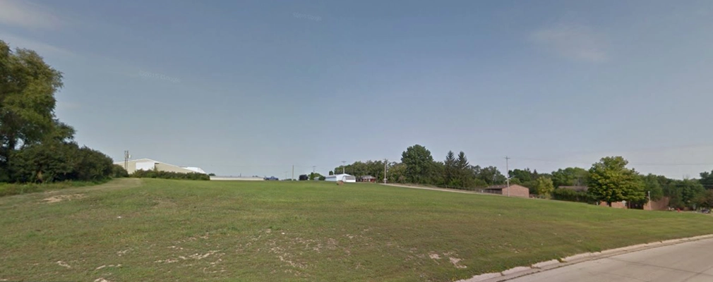 An empty, grassy lot in a suburban area. 