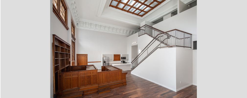 Photograph of the interior of a residential unit at Courthouse Lofts with a two-level staircase and a kitchen area in the background.