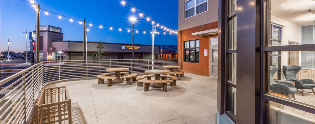 An exterior photograph of a patio area with three rounded picnic tables.
