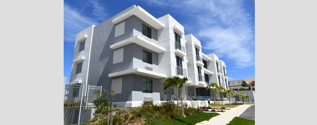 Photograph of the front and side façades of a three-story residential building. 