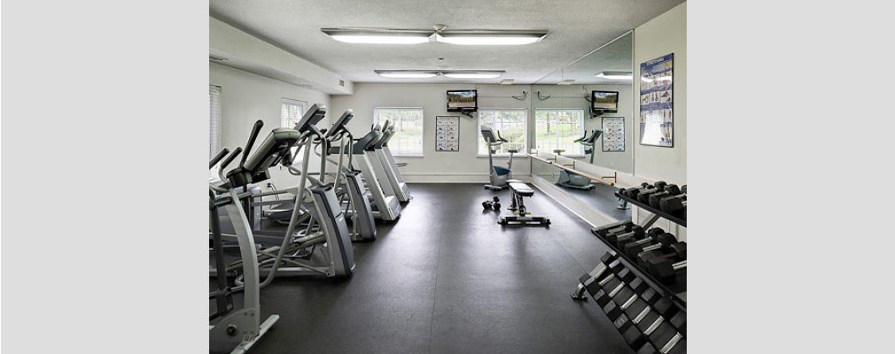 Fitness machines and weights in a small room with a large mirror on one wall.