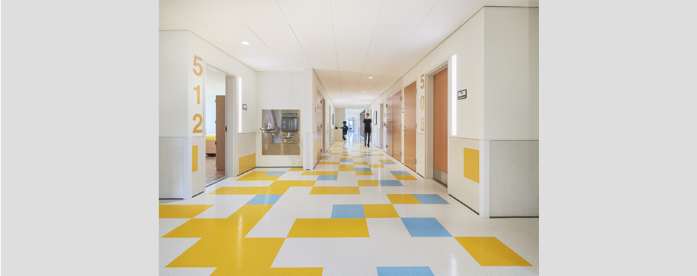 Hallway with brightly colored checkered floor and doors on both sides.