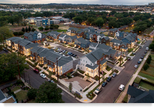 Low-angle aerial photograph taken at dusk of two- and three-story townhouses.
