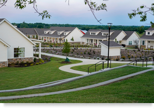 White, one-story residential buildings surrounding a large garden plot.