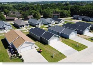 Aerial view of a small suburban community with 10 single-story homes arranged in 2 rows of 5 homes each. Each home has a front yard, narrow side yard, and two-car garage.
