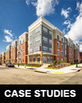 Photograph of two street façades of a four-story multifamily building.