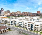 Oblique aerial view of several three-story apartment buildings with downtown Shreveport in the background.