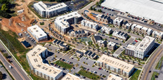 An aerial image of a housing development with several large apartment buildings and eight blocks of smaller-scale multifamily structures, including townhomes.