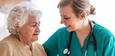 A health visitor talking to a senior woman during a home visit.