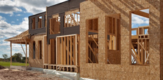 An under-construction house with wooden beams and scaffolding, showcasing the early stages of building development.