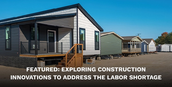 A row of prefabricated modular houses in a dirt lot.