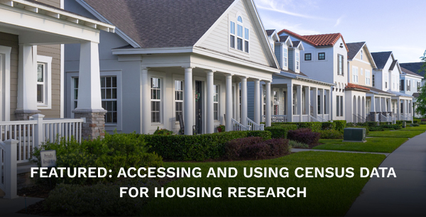 A row of houses with green lawns and shrubbery, and a sidewalk in front of them.