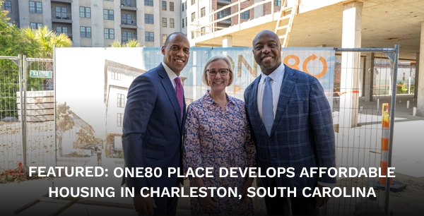 Scott Turner (left) poses with a woman and man in front of a sign that reads "One80 Place" amidst development.