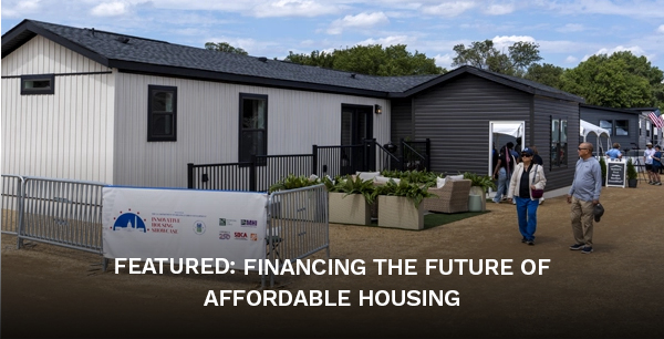 A model house on display with a group of people walking nearby.