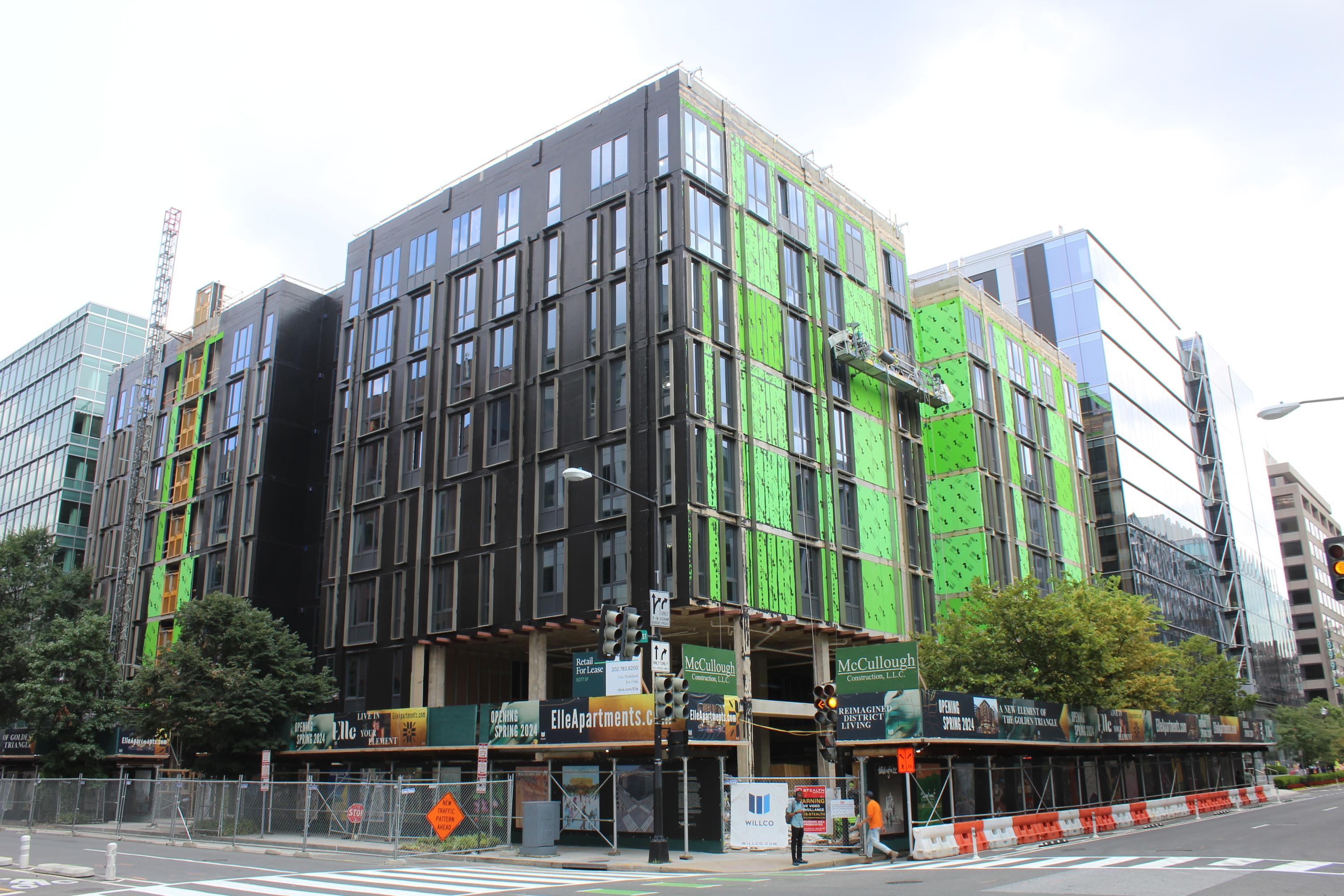 A multistory building undergoing renovation located on the corner of two streets.