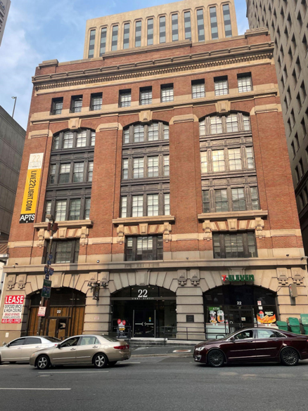 Front façade of a six-story brick building with large framed windows.