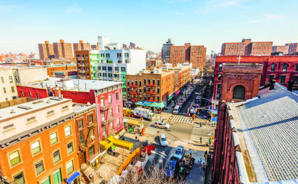 A low-angle aerial view of an urban neighborhood with busy streets and buildings of various sizes.