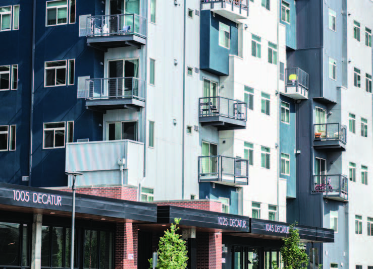 A multistory residential building with balconies and a sign '1005 Decatur' above the ground floor.