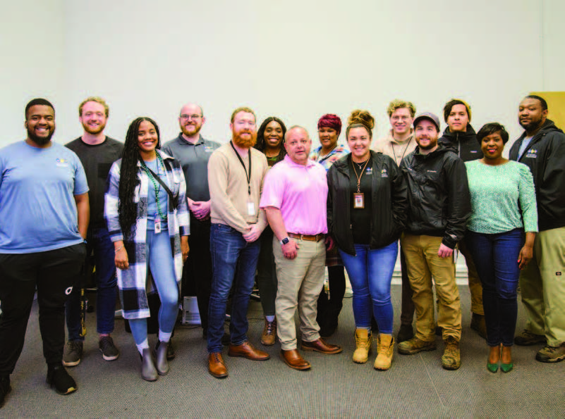 A group of 14 people standing and posing for the camera.