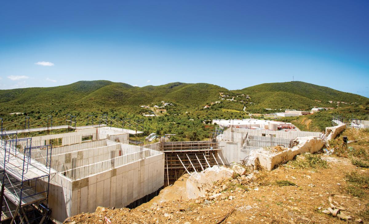 An aerial view of a building under construction with green mountains in the background.