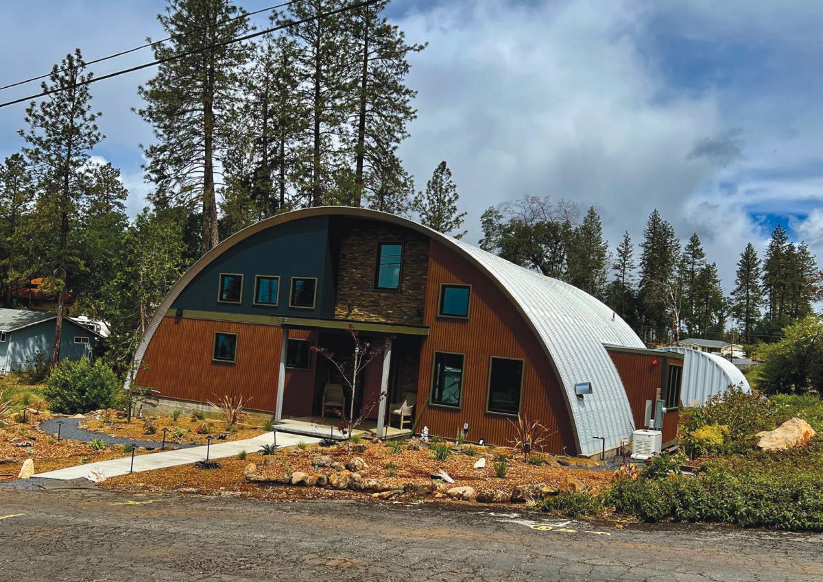 Photo of a structure with semi-circular roofline and several windows and a door on the front.