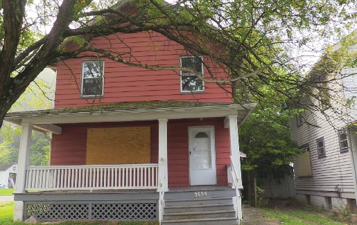 Front view of a single-family home with a boarded-up front window.