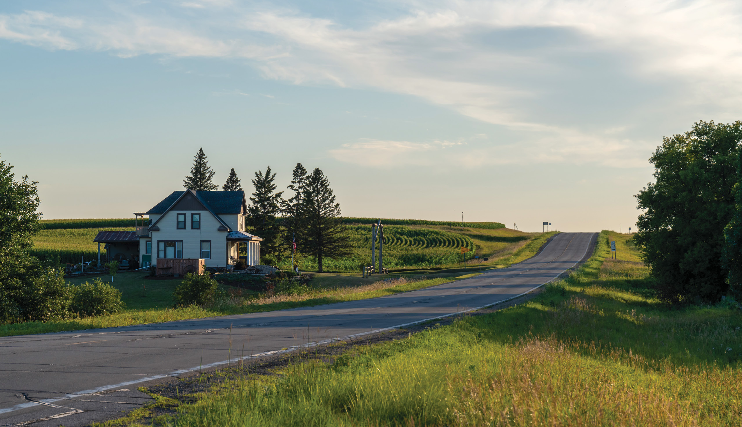 A single-family house along a quiet road surrounded by a green rural landscape.