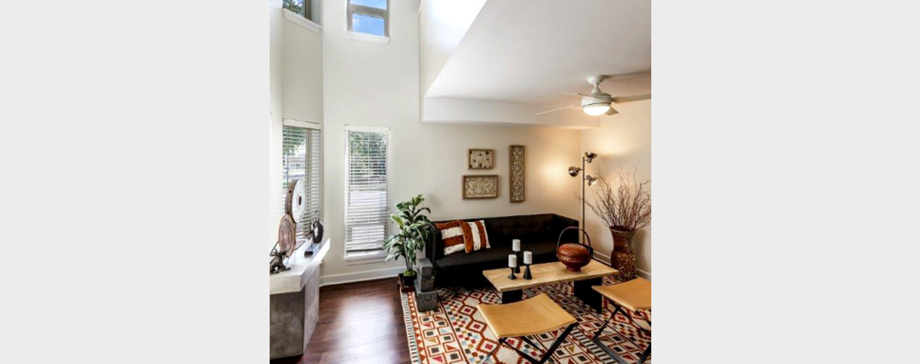 Photograph of a two-story living space with a couch, coffee table, and chairs, as well as art objects.