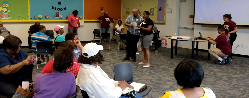 Photograph of two people making a presentation to approximately a dozen community members in a classroom.