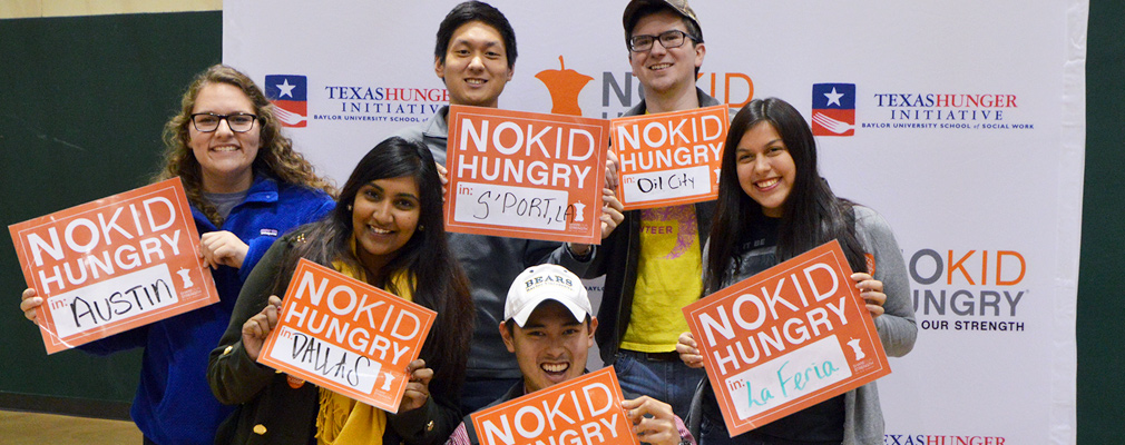 Photograph of six No Kid Hungry campaign volunteers holding signs identifying their respective cities: Austin, Dallas, Shreveport, La Feria, and Oil City.