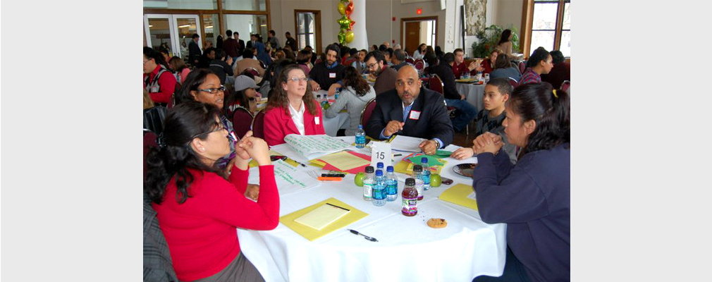 Photograph of residents working at multiple round tables in a large meeting room.