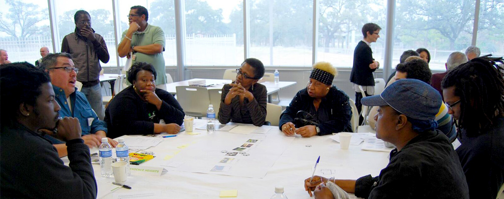 Photograph of eight residents sitting around a table in a large meeting room discussing their design preferences.