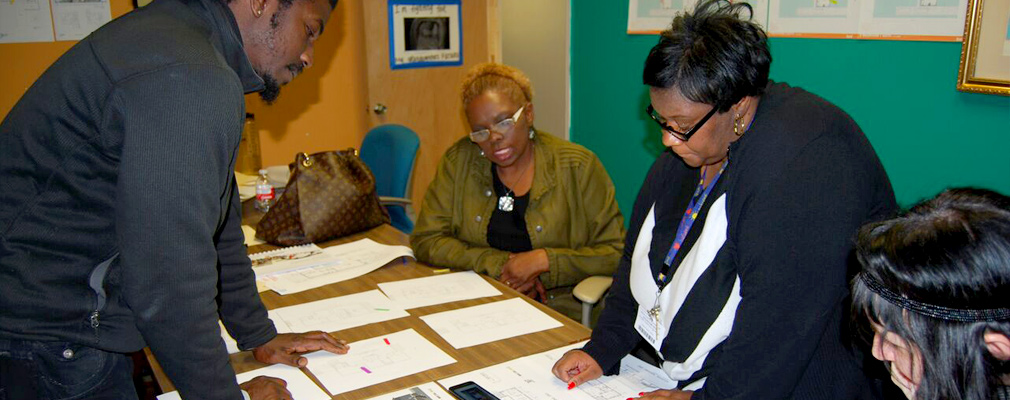 Photograph of residents viewing house layouts and discussing design elements.