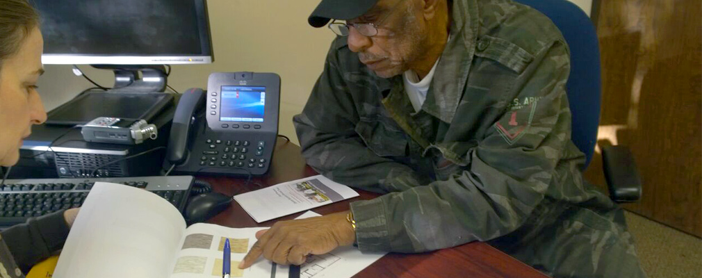 Photograph of a homeowner and design team member at a work desk discussing options in the catalogue.