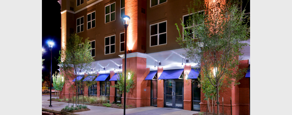 Photograph taken at night of ground-floor storefronts in a mixed-use building.