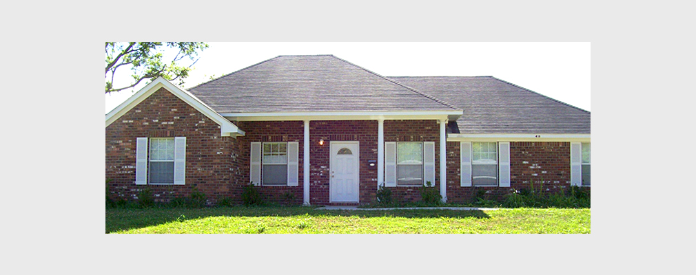 Photograph of the front façade of a brick single-family detached house.