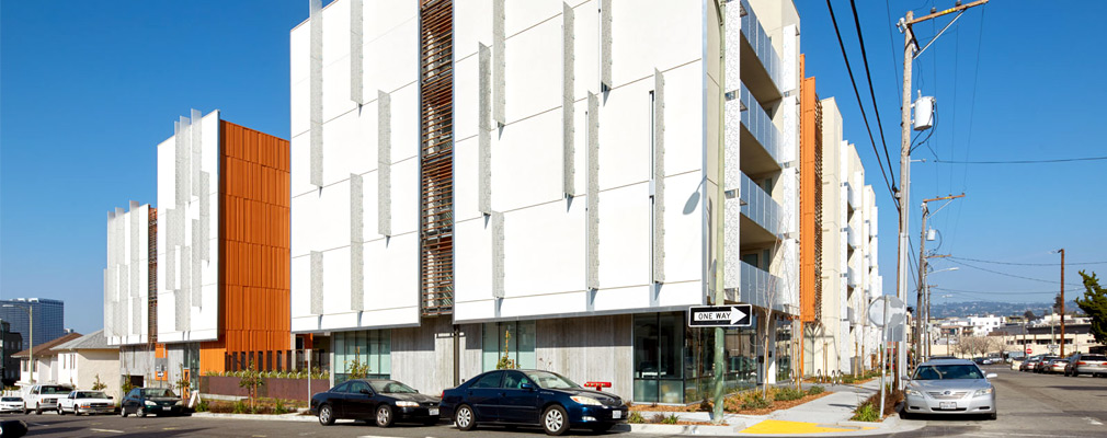 Photograph of the front and side facades of a five-story apartment building, broken into two masses and seen from the street.