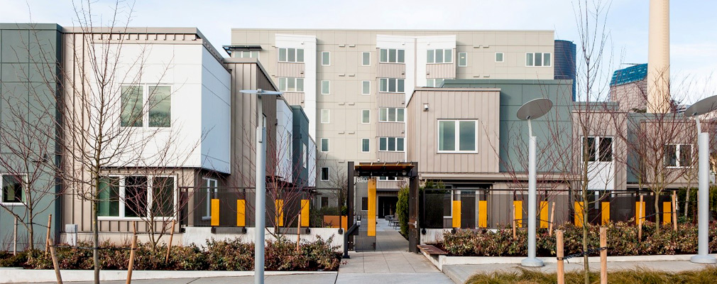 Photograph of two-story townhouse buildings in front of a seven-story apartment building.