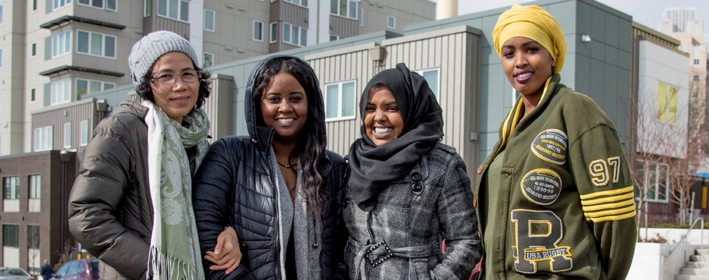 Photograph of four women standing in front of a newly constructed apartment building.