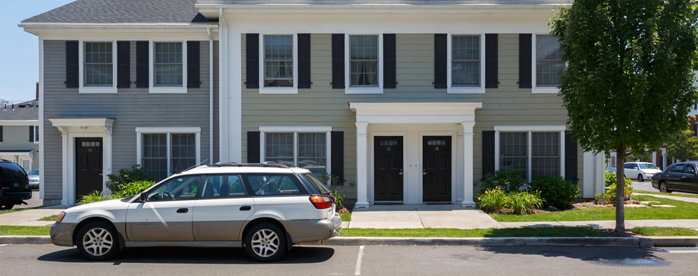 Photograph of the front façade of a three-story duplex and attached two-story house.  