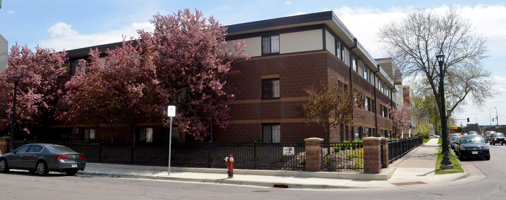 Photograph of the front and side façades of a three-story multifamily building.