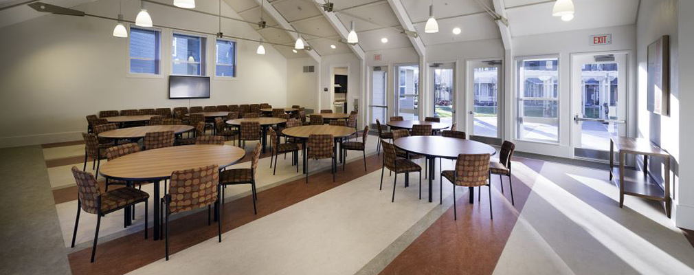 Photograph of a large room with ten oval tables and 5 chairs at each table.