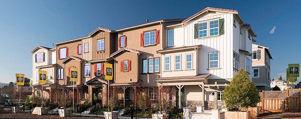 Photograph of a three-story building containing five townhouses fronted by a landscaped area.